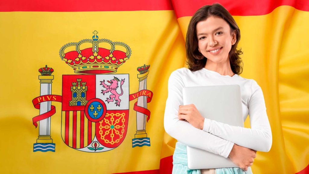 Imagem com a bandeira da espanha no fundo e menina sorrindo, abraçando um notebook na frente.